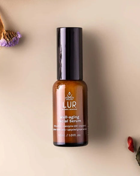 LUR well-aging facial serum in brown bottle on beige background with dried flowers, skincare product