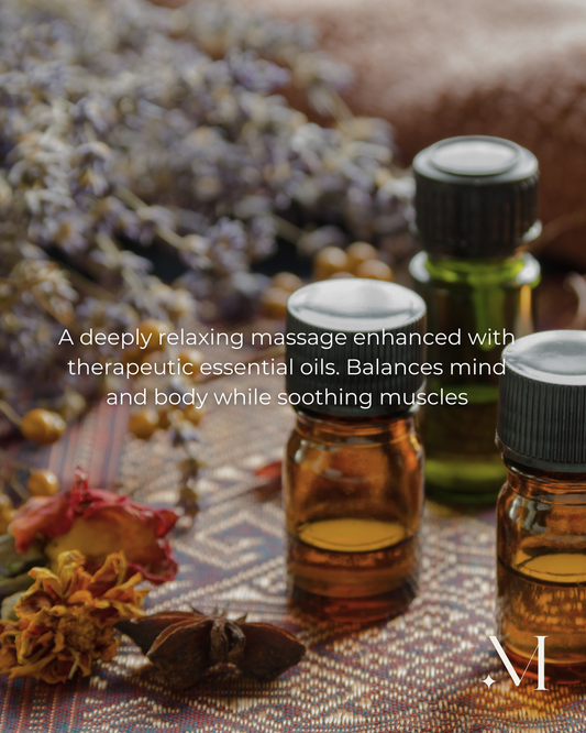 Aromatherapie massageflesjes met essentiële oliën en gedroogde bloemen op een spa-achtig doekje.