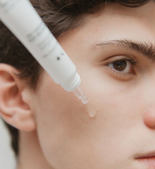 Close-up van een huidverzorgingsserum dat op de wang van een jong persoon wordt aangebracht voor gezichtsverzorging.