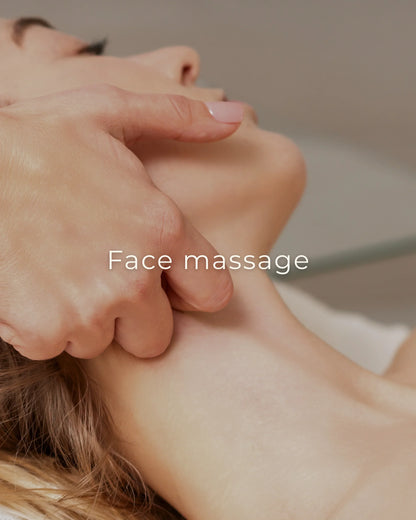 Close-up van een ontspannende gezichtsmassage, waarbij een hand zachtjes de wang en kaaklijn van een vrouw masseert.