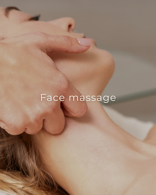 Close-up van een ontspannende gezichtsmassage, waarbij een hand zachtjes de wang en kaaklijn van een vrouw masseert.