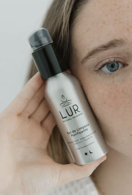 Vrouw houdt een flesje LUR natuurlijke huidverzorgingsgel dicht bij haar gezicht.